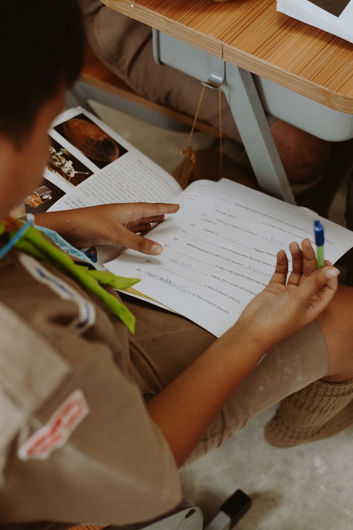 Focused student concentrating on a classroom test, holding a pen, surrounded by educational material.